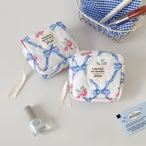 Flat lay of floral quilted cotton makeup bags with elegant blue ribbon zipper pulls