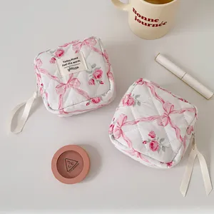 Close-up of quilted makeup bag featuring pink floral print and ribbon zipper detail