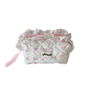 Quilted floral cosmetic bag with pink bows, lace trim, and ribbon zipper pull