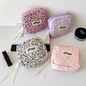 Detail view of small quilted cosmetic bags in four patterns with long ribbon zippers