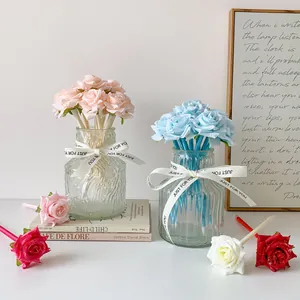 Vue détaillée de stylos rose colorés dans un vase en verre rayé avec ruban blanc