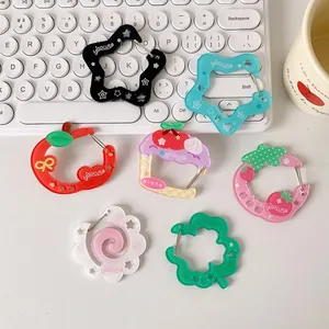 Set of 7 acrylic cartoon carabiners including colorful stars and fruits on a white desk