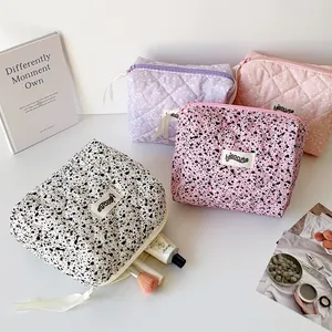 Close-up of quilted cosmetic bags in ink splash and polka dot patterns with ribbons