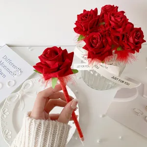 Detail of red artificial rose ballpoint pen with delicate feather and gift ribbon