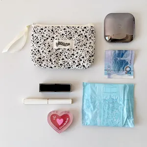 Vista plana de bolsa acolchada con manchas de tinta y artículos de belleza diarios