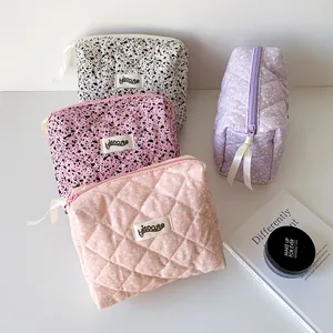 Close-up of quilted and ink-splatter cosmetic bags with ribbon zippers and brand labels