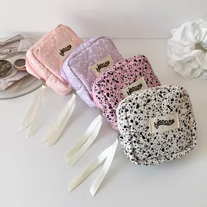 Detailed close-up of quilted cosmetic bags with ink splash patterns and ribbon zippers