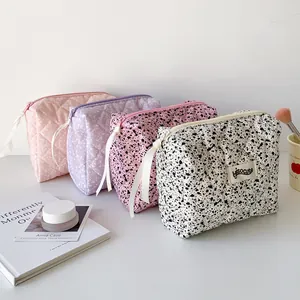 Quilted makeup bags with ink-splash print and ribbon zippers in various pastel colors