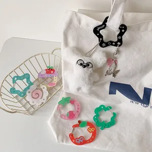 Detail of acrylic carabiner charms with plush dog pendant on a white canvas bag