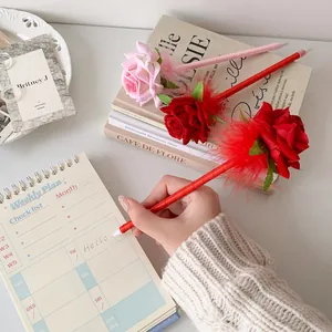 Detail of rose-shaped gift pens with silk petals and feathers on a vintage desk setup