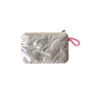 Quilted silver makeup bag with butterfly embroidery and pink lanyard on white background