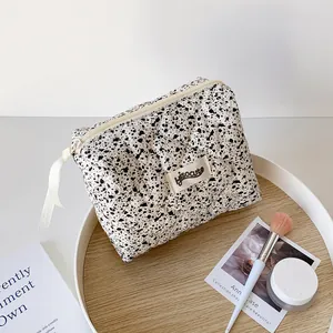Detail of quilted splatter pattern makeup bag with branded tag and cream zipper