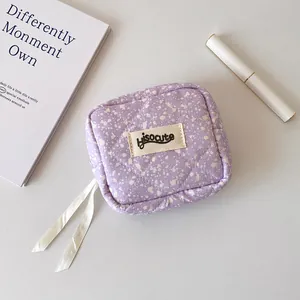 Detail of purple quilted mini bag with ink splash pattern and white ribbon zipper pulls