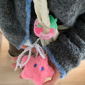Close-up of a pink plush star keychain with pearl beads and strawberry charm accessory