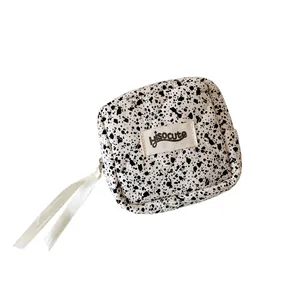 Minimalist ink-splatter quilted small square pouch with branded label and silk ribbon zipper