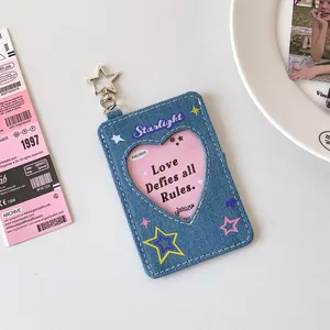 Blue denim photocard holder with star embroidery and heart-shaped window on white desk