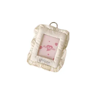 Cream fabric photo card holder with ruffled edges and silver metal D-ring keychain
