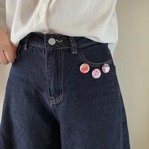 Three pink cartoon pins styled on blue denim pocket as cute decorative accessories