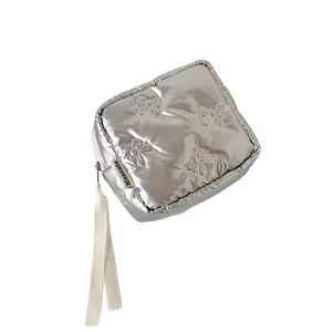 Silver quilted cosmetic bag with bow patterns and zipper closure in a 45-degree view