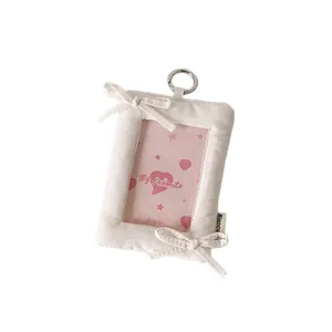 Minimalist white fabric photocard holder with bows and a metal ring for display