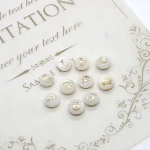 Détail de perles en nacre blanche avec chiffres dorés pour bijoux DIY