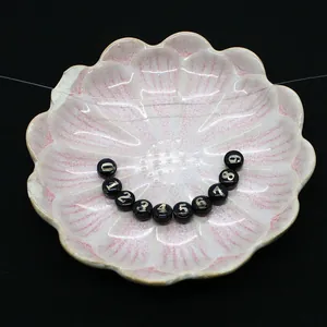 Perles rondes plates en résine noire avec chiffres dorés pour bijoux DIY dans un plat