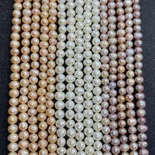Detail of natural freshwater pearls 2-3mm in white, purple, and orange on dark background