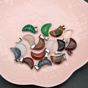 Polished moon-shaped natural stone crystal pendants with silver metal clasps in a dish