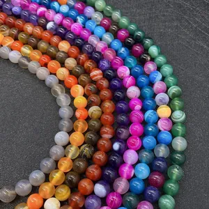 Vue macro de perles rondes en agate rayée colorée en bleu rose et orange pour bijoux DIY