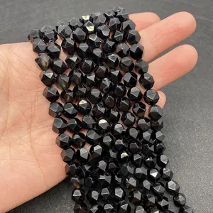 Detailed view of faceted black onyx beads held in hand for size and texture comparison