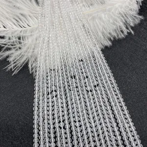 Macro detail of faceted white crystal beads on black fabric with white feathers