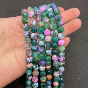 Detailed view of colorful dragon vein agate beads held in hand for DIY jewelry making