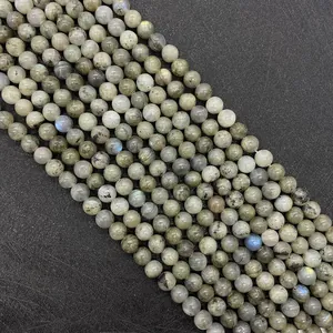 Macro di perle tonde in labradorite naturale con riflessi blu e iridescenze dorate su nero