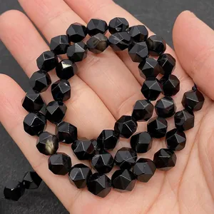 Macro shot of faceted black onyx beads in hand showing geometric cut and glossy finish