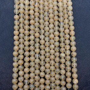 Macro detail of vertical strings of golden rutilated quartz round beads on black tray