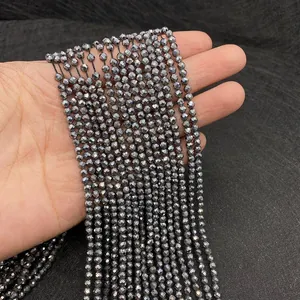 Détail macro de perles d'hématite facettées montrant un éclat métallique sur un tissu noir
