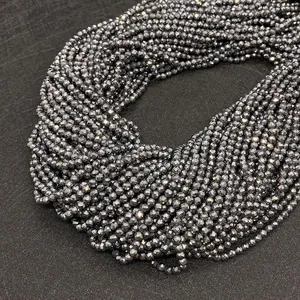 Vue macro de perles d'hématite facettées au fini métallique et à la coupe ronde précise