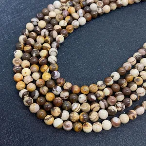 Gros plan de perles en jaspe zébré naturel aux motifs bruns pour création de bijoux
