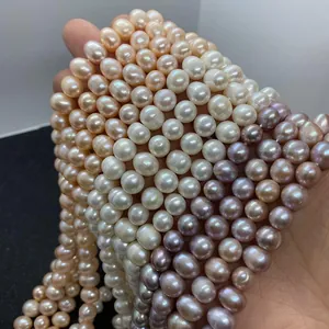 Macro detail of mixed white, pink, and purple freshwater pearls held in hand for jewelry DIY