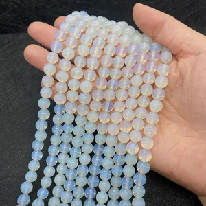 Primo piano di perle di opalite traslucide per gioielli fai-da-te tenute in mano