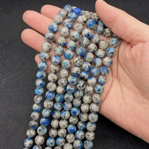 Dettaglio di perle tonde in granito K2 con macchie blu e base grigia sulla mano