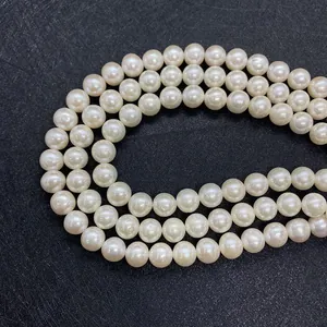 Close-up of triple-strand high-luster white freshwater pearl necklace on black texture