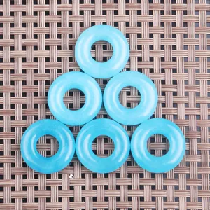 Macro shot of six light blue translucent stone donut pendants on a dark woven mat