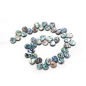 Macro view of teardrop abalone shell beads with iridescent green and blue colors