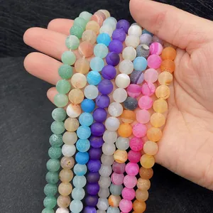 Hand holding assorted matte frosted natural agate stone beads in vibrant mixed colors