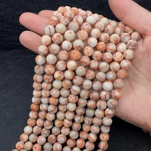 Close-up of hand holding round red net jasper stone beads for DIY jewelry making