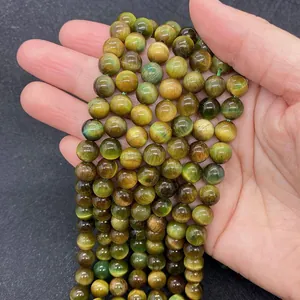 Macro view of green and yellow tiger eye stone beads on palm showing cat eye effect