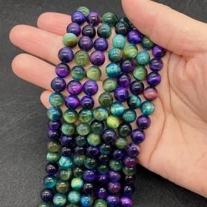 Close-up of vibrant multicolored tiger eye stone beads held in hand for jewelry making