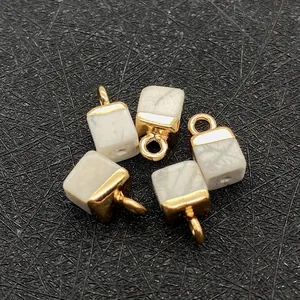 Detail of five marble-textured cube pendants with gold caps and loops for DIY jewelry