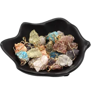 Irregular raw crystal pendants with gold wire wrapping in a black ceramic bowl